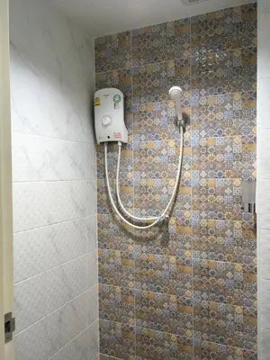 a shower with a hose attached to a tiled wall at Baan Wanchart in Bangkok