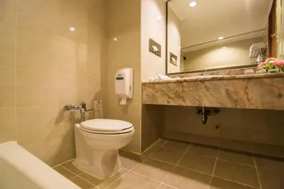 a bathroom with a toilet and a sink and a mirror at Bangkok Palace Hotel in Bangkok