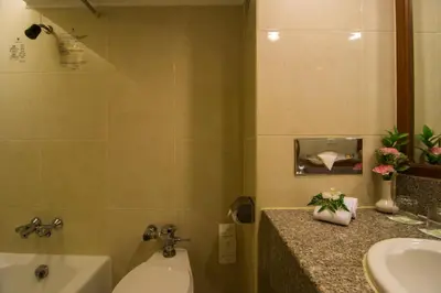 a bathroom with a sink and a toilet and a tub at Bangkok Palace Hotel in Bangkok