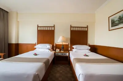 a hotel room with two beds with flowers on them at Bangkok Palace Hotel in Bangkok