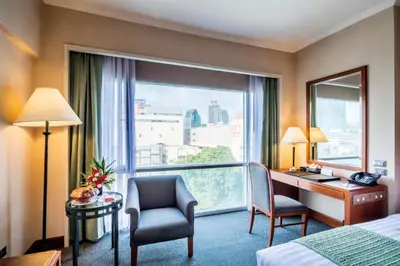 a hotel room with a desk and a window at Bangkok Palace Hotel in Bangkok