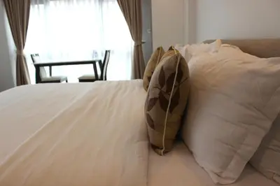 a bed with white sheets and pillows with a window at V One Pride-Sukhumvit 22, Bangkok in Bangkok