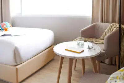 a bedroom with a bed and a table and a chair at Kritthai Residence in Bangkok