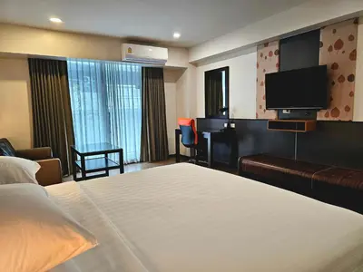 a hotel room with a bed and a flat screen tv at Dynasty Grande Hotel in Bangkok