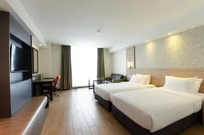a hotel room with two beds and a flat screen tv at Dynasty Grande Hotel in Bangkok