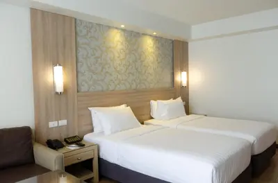 a hotel room with two beds and a couch at Dynasty Grande Hotel in Bangkok