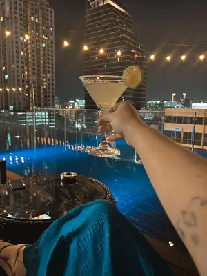 a woman holding a martini glass on top of a building at De Prime Rangnam Hotel in Bangkok