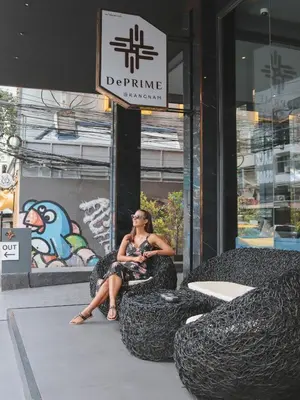 a woman sitting in a chair in front of a store at De Prime Rangnam Hotel in Bangkok