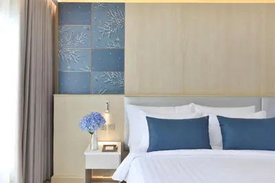 a bedroom with a bed with blue and white pillows at Centre Point Plus Hotel Pratunam in Bangkok