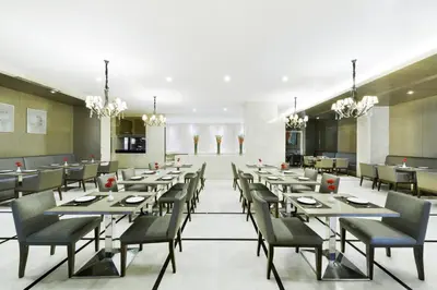 a dining room with tables and chairs and chandeliers at Centre Point Hotel Chidlom Bangkok in Bangkok