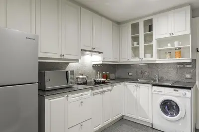 a kitchen with white cabinets and a washer and dryer at Centre Point Hotel Chidlom Bangkok in Bangkok