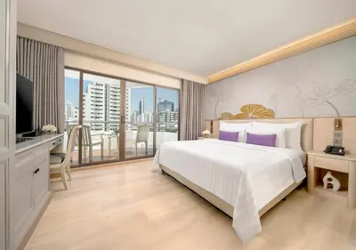 a bedroom with a large white bed and a balcony at Centre Point Sukhumvit 10 in Bangkok
