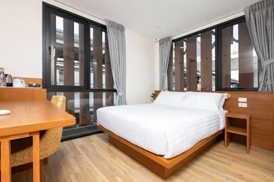 a bedroom with a bed and a desk and windows at Sukhon Hotel - SHA Plus in Bangkok