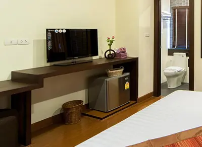 a room with a bed and a television on a counter at Tara Place Hotel Bangkok in Bangkok