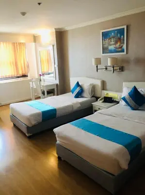 a hotel room with two beds and a table at Bay Hotel Srinakarin in Bangna