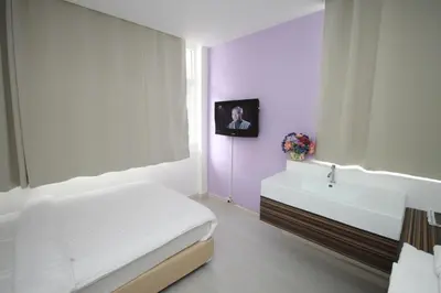 a bedroom with a white bed and a sink at Nantra Ekkamai Hotel in Bangkok