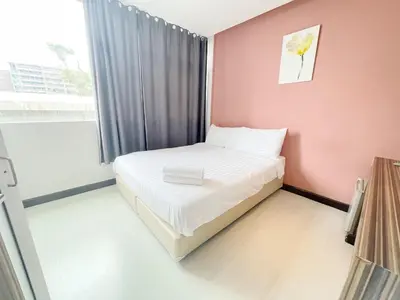 a small bed in a room with a pink wall at Nantra Ekkamai Hotel in Bangkok