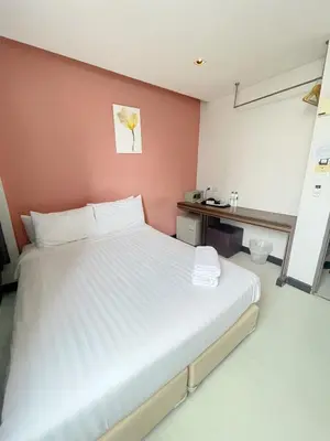 a bedroom with a white bed and a pink wall at Nantra Ekkamai Hotel in Bangkok