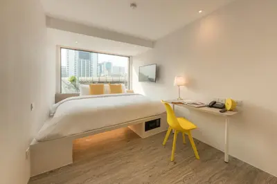 a bedroom with a bed and a desk and a yellow chair at Yello Rooms Hotel Victory Monument in Bangkok