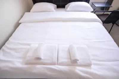 a bed with white sheets and towels on it at ninaguesthouse in Bangkok
