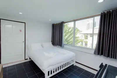 a bed in a room with a large window at NK Guesthouse 2 in Bangkok