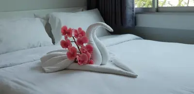 a white towel with a flower on a bed at NK Guesthouse 2 in Bangkok