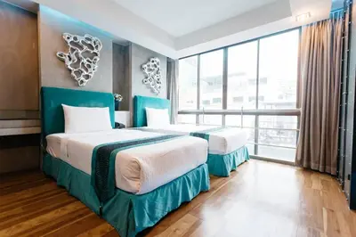 a hotel room with two beds and a large window at Blutique Hotel in Bangkok