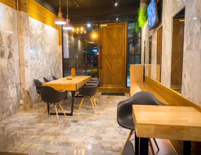 a restaurant with a wooden table and chairs at Comfy Bed Hostel in Bangkok
