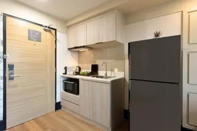 a kitchen with a black refrigerator and a sink at Oakwood Hotel & Residence Bangkok in Bangkok