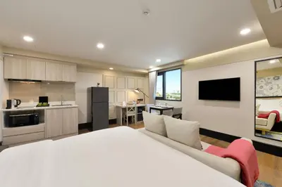a large bedroom with a white bed and a kitchen at Oakwood Hotel & Residence Bangkok in Bangkok
