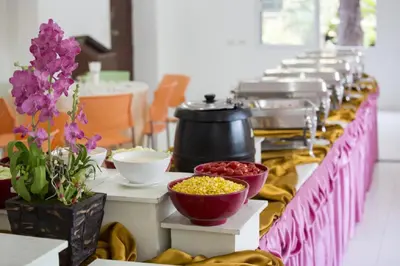 a long buffet line with bowls of food and flowers at The Loft Resort Bangkok in Bangkok