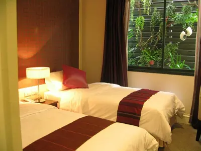 a hotel room with two beds and a window at Aphrodite Inn Bangkok in Bangkok