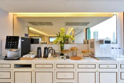 a large kitchen with white cabinets and appliances at Centre Point Plus Hotel Silom - Newly Renovated in Bangkok