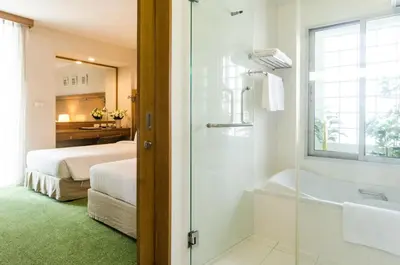 a bathroom with a shower and a bed and a tub at AT EASE saladaeng by AETAS in Bangkok