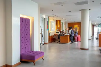 a group of people standing in a lobby with a purple couch at AT EASE saladaeng by AETAS in Bangkok