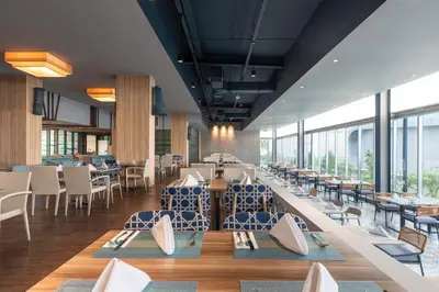 a dining room with tables and chairs and windows at Centara Life Government Complex Hotel & Convention Centre Chaeng Watthana in Bangkok