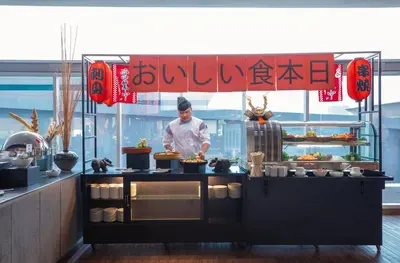 a chef preparing food behind a counter in a restaurant at Centara Life Government Complex Hotel & Convention Centre Chaeng Watthana in Bangkok