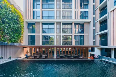 an external view of a building with a swimming pool at Arcadia Suites Ploenchit Bangkok in Bangkok