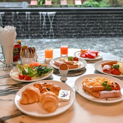 a table topped with plates of food and drinks at Arcadia Suites Ploenchit Bangkok in Bangkok
