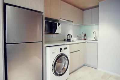 a kitchen with a refrigerator and a washing machine at Arcadia Suites Ploenchit Bangkok in Bangkok