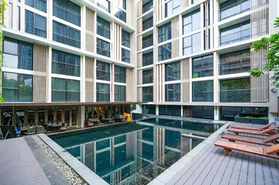 a building with a swimming pool in front of a building at Arcadia Suites Ploenchit Bangkok in Bangkok