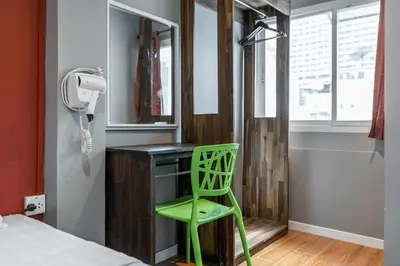 a green chair sits at a desk in a bedroom at The Richy Place Guest House in Bangkok