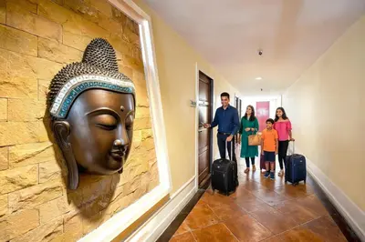 a family with luggage walking down a hallway with a head on the wall at Royal Ivory Sukhumvit Nana in Bangkok