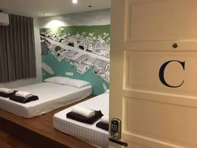 two beds in a room with a painting on the wall at 99 Hostel Khaosan in Bangkok