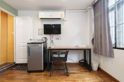 a small kitchen with a table and a refrigerator at 99 Hostel Khaosan in Bangkok