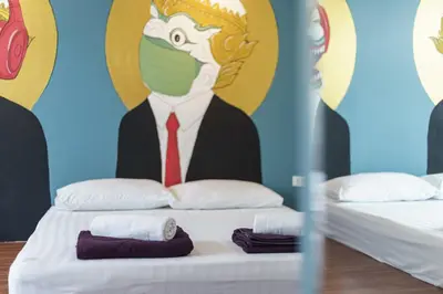 a room with two beds with a man wearing a mask at 99 Hostel Khaosan in Bangkok
