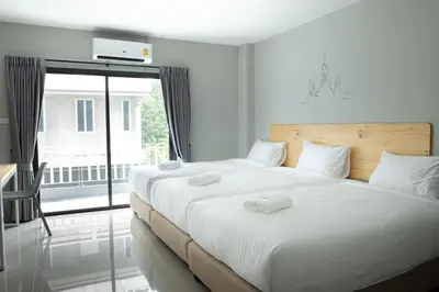 a bedroom with two beds and a large window at Fine Bed Hotel in Nonthaburi