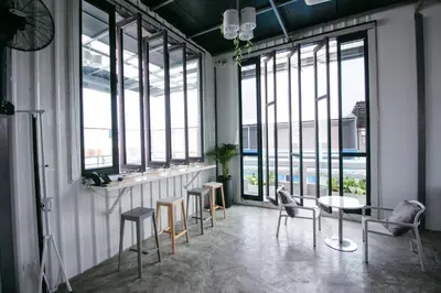 a room with chairs and a bar with windows at Fine Bed Hotel in Nonthaburi