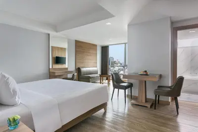 a bedroom with a bed and a desk and chairs at Adelphi Grande Sukhumvit in Bangkok