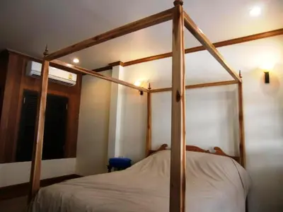 a wooden four poster bed in a bedroom at The Royal ThaTien Village in Bangkok